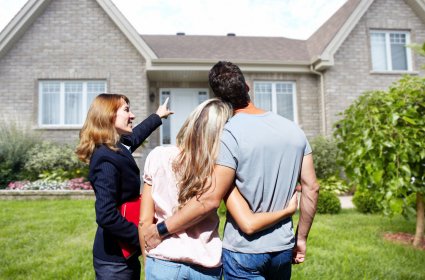 Real Estate agent woman with clients near new house.